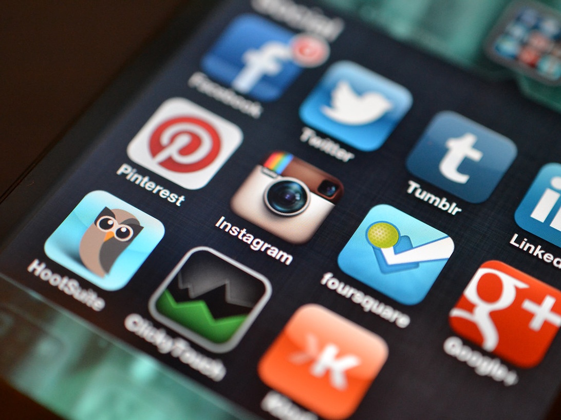 Närbild av en smartphoneskärm som visar olika ikoner för sociala medier-appar inklusive Facebook, Twitter, Pinterest, Instagram, Tumblr och andra sociala nätverksappar. Bilden är skarp och tydlig och visar de färgglada appikonerna mot en mörk skärmbakgrund.