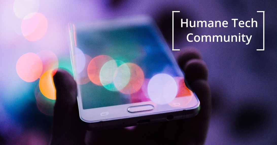 Närbild på smartphone med texten Humane Tech Community på skärmen och bokeh-ljus.